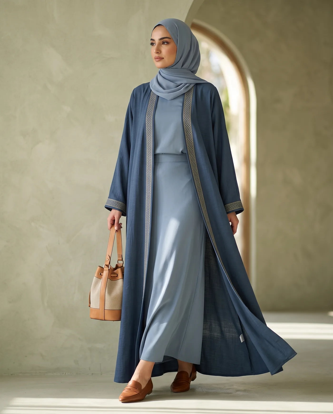 An embroidered open abaya in slate blue, worn over a matching slip